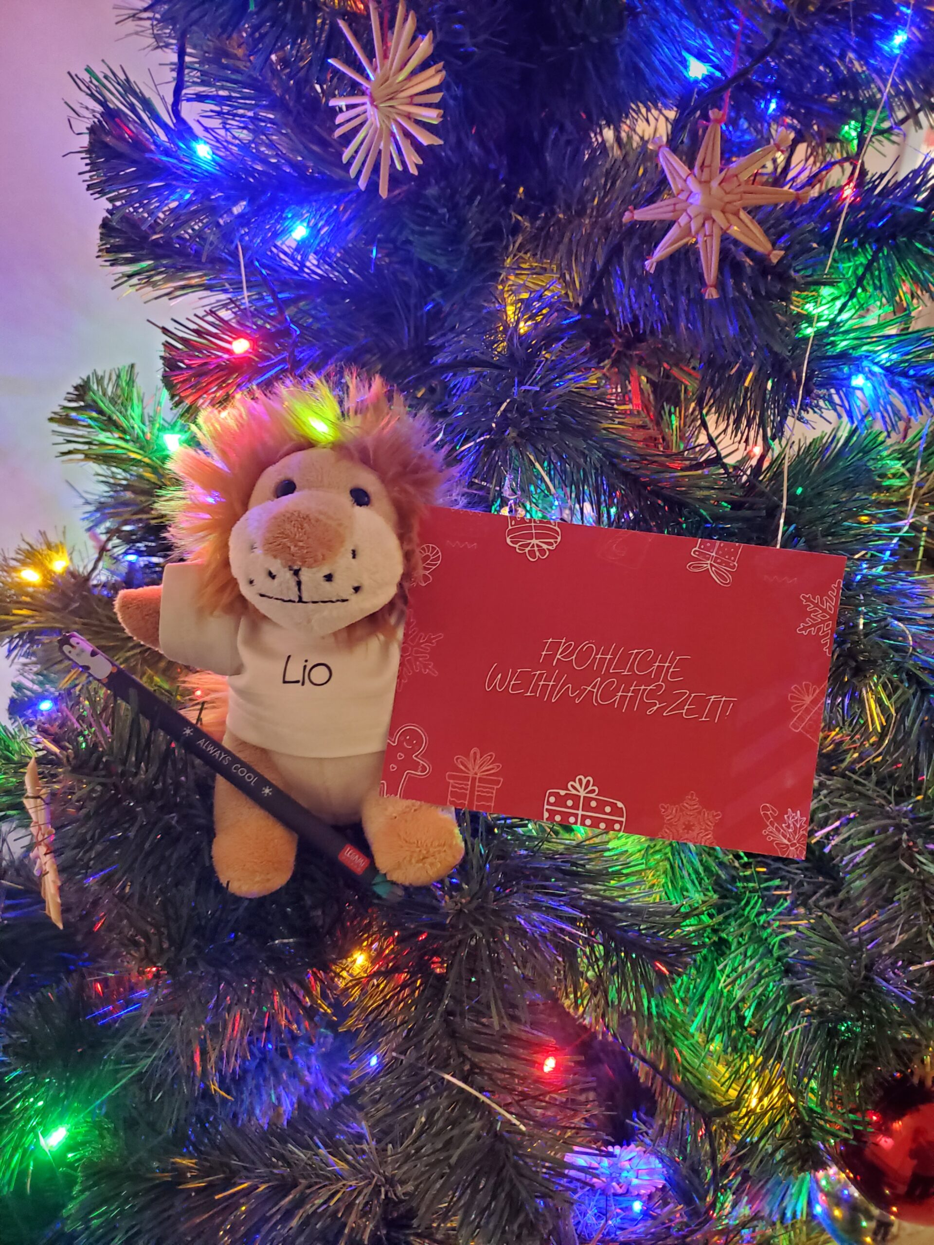 Löwenplüschtier sitzt im Weihnachtsbaum mit Weihnachtskarte